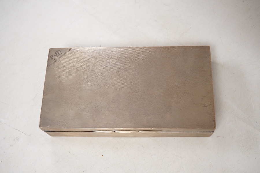 A George VI engine turned silver mounted rectangular cigarette box, by A. Wilcox, Birmingham, 1938, 17cm, with engraved inscription.